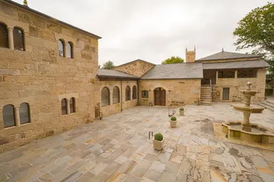 a large stone building with a fountain in the courtyard at Hotel As Torres da Hermida in Monterroso