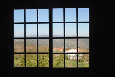 a window with a view of a house seen through it at Casa O Torgal in Parada del Sil