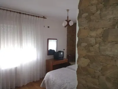 a bedroom with a stone wall and a bed and a television at Arume in Bóveda