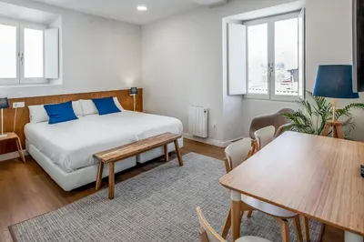 a bedroom with a bed and a table and chairs at SNÖ Camino do Eume Apartamentos in Puentedeume