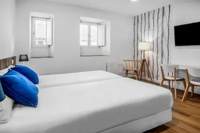 a bedroom with two beds and a table and chairs at SNÖ Camino do Eume Apartamentos in Puentedeume