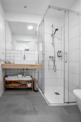 a white bathroom with a shower and a sink at SNÖ Camino do Eume Apartamentos in Puentedeume