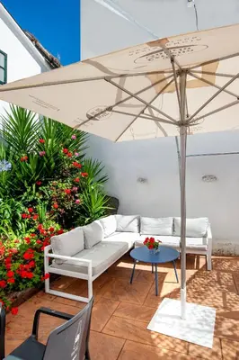 a patio with a white couch and an umbrella at SNÖ Camino do Eume Apartamentos in Puentedeume
