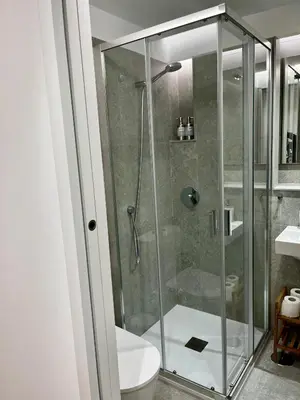 a bathroom with a glass shower with a toilet at Hostal Charo II in Santiago de Compostela