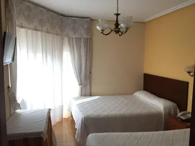 a hotel room with two beds and a window at Hotel Restaurante Derby in Carballino