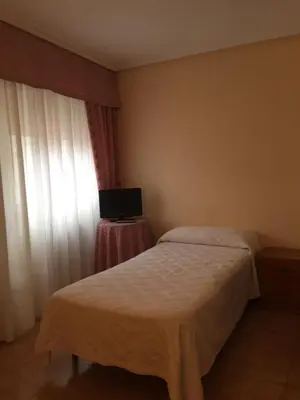 a bedroom with a bed and a window with a television at Hotel Restaurante Derby in Carballino