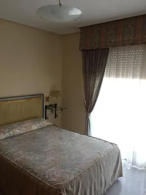 a bedroom with a bed and a large window at Hotel Restaurante Derby in Carballino
