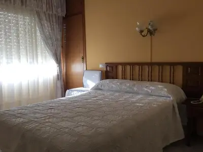 a bedroom with a white bed and a window at Hotel Restaurante Derby in Carballino