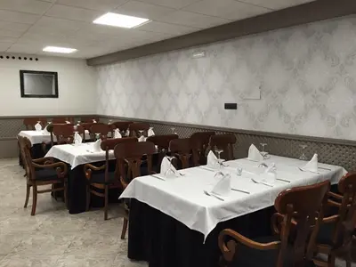 a dining room with tables and chairs with white table cloth at Hotel Restaurante Derby in Carballino