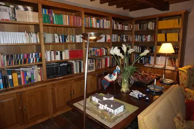 a living room with a table and a library with books at Hotel Rural Palacio de Prelo in Boal