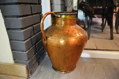 a brown vase sitting next to a brick wall at O Prado do Forno in O Barco de Valdeorras
