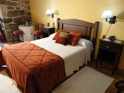 a hotel room with a large bed with orange pillows at Casa Rural Rectoral de Candás in Rairiz de Veiga
