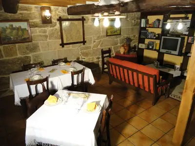 a restaurant with two tables and chairs and a tv at Casa Rural Rectoral de Candás in Rairiz de Veiga