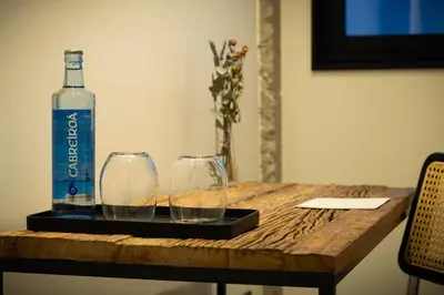 a bottle of water and two glasses on a wooden table at AFTER Hotel in Bastiagueiro