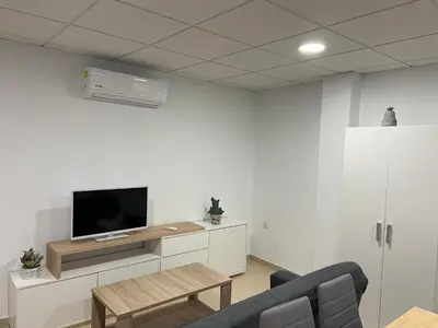 a living room with a tv and a couch and a table at Os Arcos - Apartamentos Turísticos in Portomarin