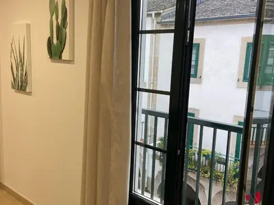 an open window with a view of a house at Os Arcos - Apartamentos Turísticos in Portomarin