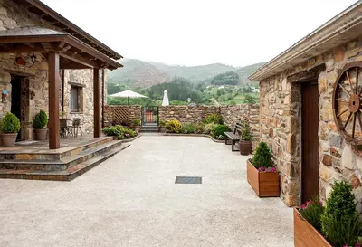 a patio with a stone building with a clock on it at Apartamentos Rurales Posada de las Hoces in Bustiello de Paredes