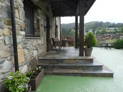 a stone house with stairs leading to a patio at Apartamentos Rurales Posada de las Hoces in Bustiello de Paredes