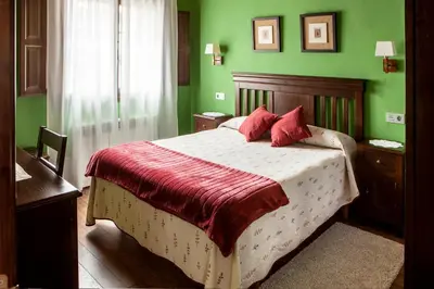 a green bedroom with a bed with red pillows at Apartamentos Rurales Posada de las Hoces in Bustiello de Paredes