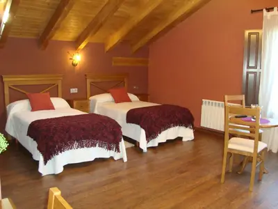 a bedroom with two beds and a table and a chair at Apartamentos Rurales Posada de las Hoces in Bustiello de Paredes