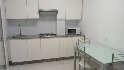 a kitchen with white cabinets and a table and a microwave at Enseñanza in Ourense