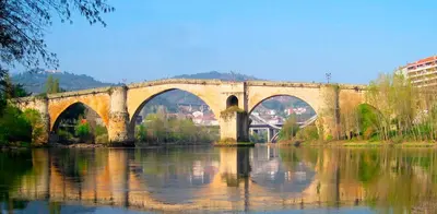 a stone bridge over a river with reflections in the water at Enseñanza in Ourense