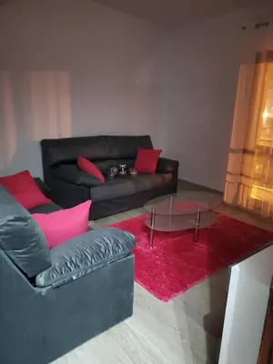 a living room with a black leather couch and a red rug at Piso termal in Ourense