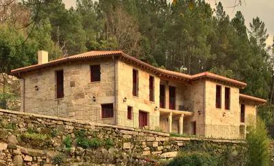 a building on a stone wall next to a mountain at Gandarela Turismo Rural in Ourense
