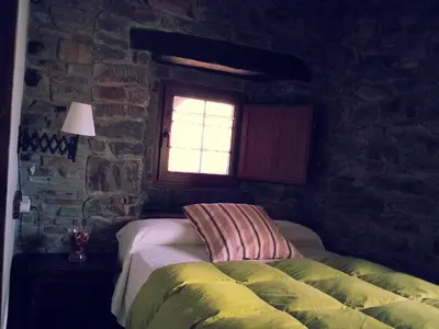 a bedroom with a bed in a stone wall at Hostal De Montaña La Aldeya in Villablino