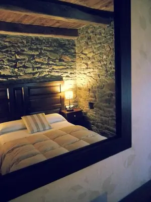 a bedroom with a bed in a stone wall at Hostal De Montaña La Aldeya in Villablino