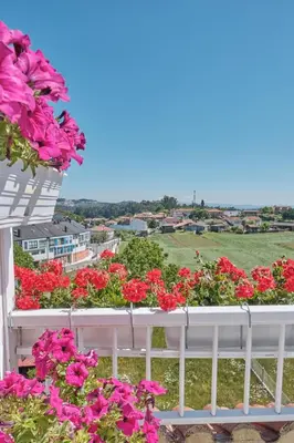 a white balcony with pink flowers on it at Peregrina Pensión 2 in O Pedrouzo
