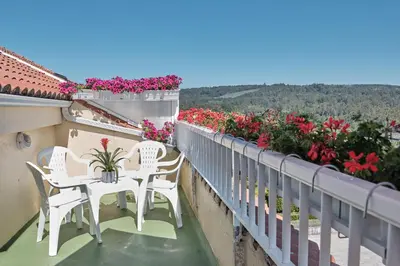 a balcony with white chairs and pink flowers at Peregrina Pensión 2 in O Pedrouzo