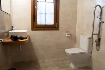 a bathroom with a toilet and a sink and a window at Apartamentos Rurales Camín Real in La Caridad