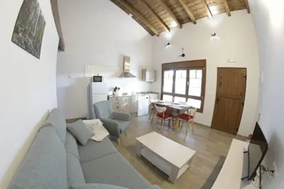 a living room and kitchen with a couch and a table at Apartamentos Rurales Camín Real in La Caridad