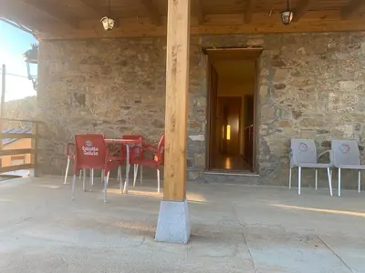 a table and chairs on a patio with a stone wall at La casa de la valla azul (San Miguel de Langre) in San Miguel de Langre