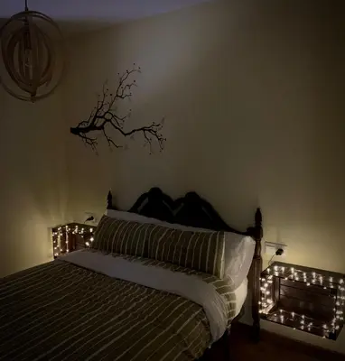 a bedroom with a bed with lights on it at La casa de la valla azul (San Miguel de Langre) in San Miguel de Langre