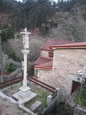 a cross in front of a building with a church at Casa Do Conde in Caldas de Reis