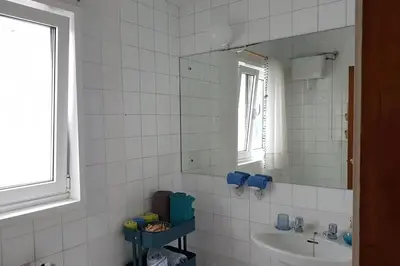 a white tiled bathroom with a sink and a mirror at Amplio y luminoso piso en el centro de Ourense in Ourense