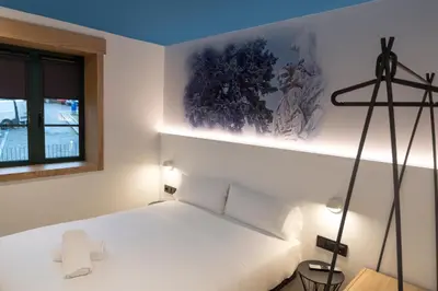 a bedroom with a bed with white sheets and a window at Alameda Rooms Santiago in Santiago de Compostela