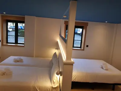 two beds in a room with two windows at Alameda Rooms Santiago in Santiago de Compostela