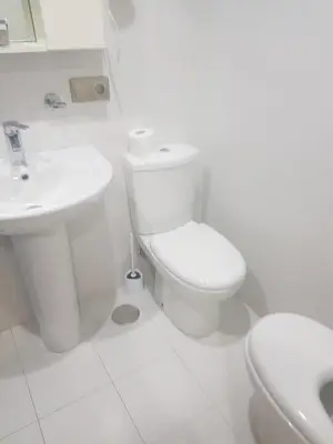 a white bathroom with a toilet and a sink at Apartamentos Burela in Burela de Cabo