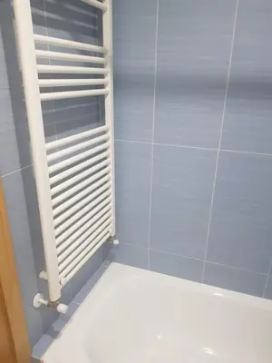 a blue tiled bathroom with a white radiator at Apartamentos Burela in Burela de Cabo