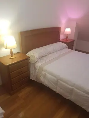 a bedroom with a bed and two night stands with lamps at Apartamentos Burela in Burela de Cabo