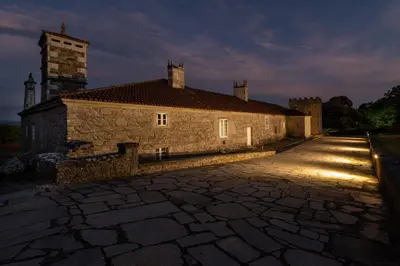 an old stone building with a tower in the background at Pazo de San Pedro de Bembibre in Taboada