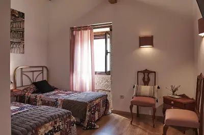 a bedroom with two beds with blankets and a picture on the wall at Parga Natura Alojamiento in Parga