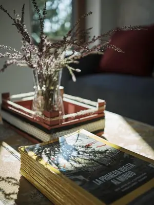 a table with a book and a vase with flowers on it at Parga Natura Alojamiento in Parga