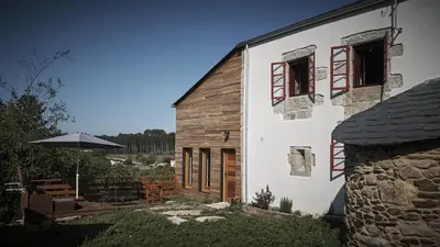 a white building with windows and an umbrella at Parga Natura Alojamiento in Parga
