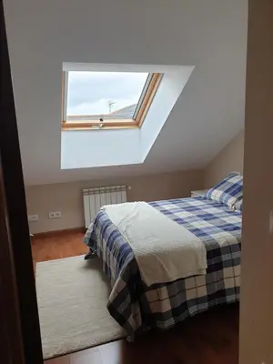 a attic bedroom with two beds and a window at Apartamento Ático Cine Colón in Ribadeo