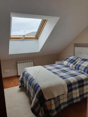 a attic bedroom with two beds and a window at Apartamento Ático Cine Colón in Ribadeo