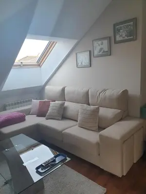 a white couch in a living room with a window at Apartamento Ático Cine Colón in Ribadeo